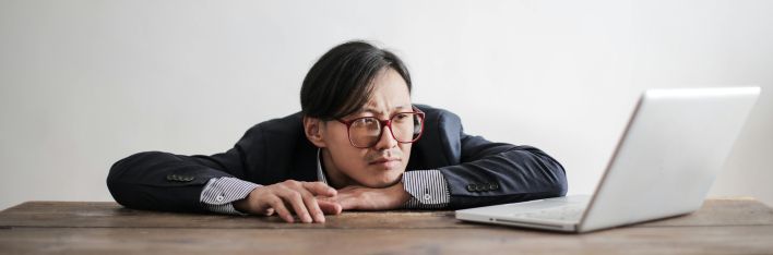 Bored formal man watching laptop at desk